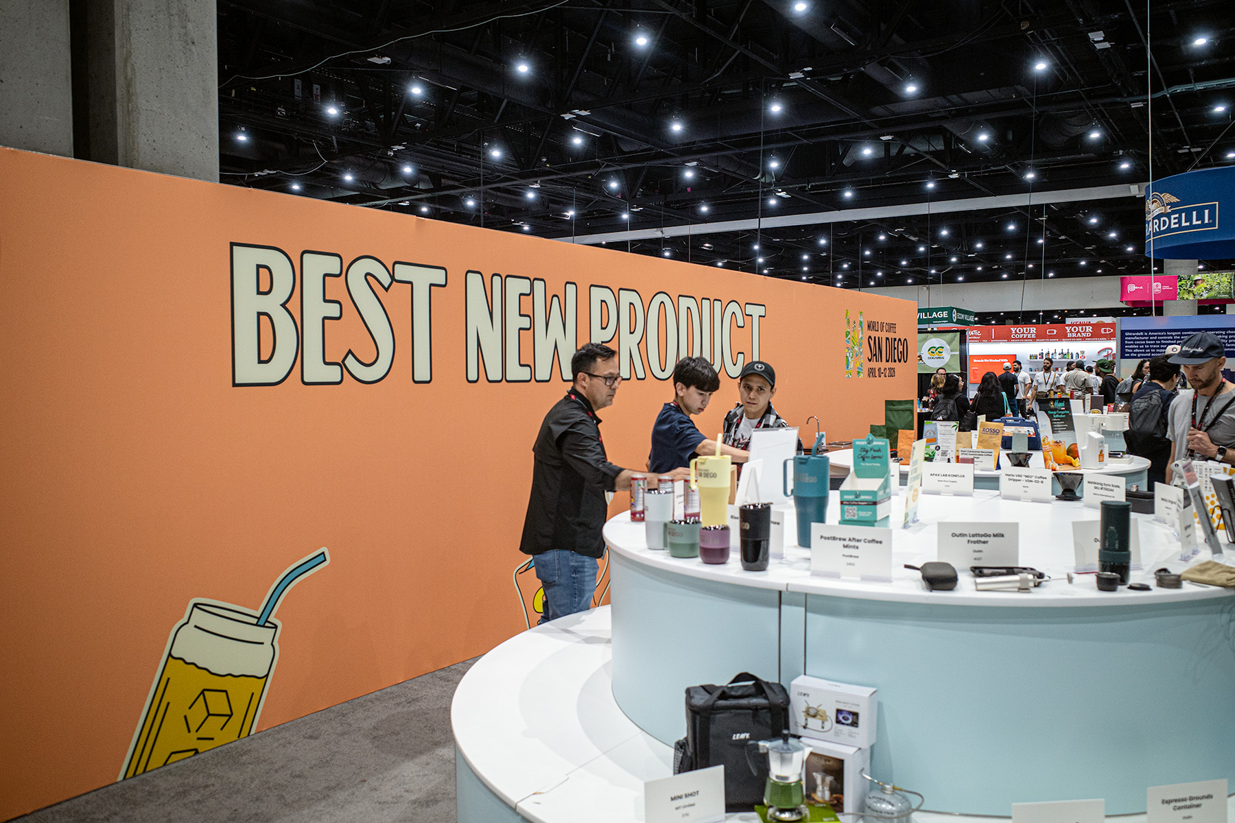 best new product 3 men hover over merch displays, as a coral wall behind them reads "Best New Product."