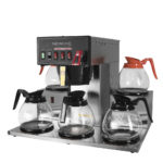 Angled view of stainless steel cabinet, black plastic face plate, five burners, hot water faucet FC-5 brewer, shown with glass carafes