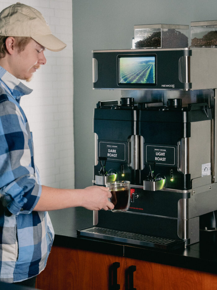 A man lifts a cup of coffee from the Infiniberew